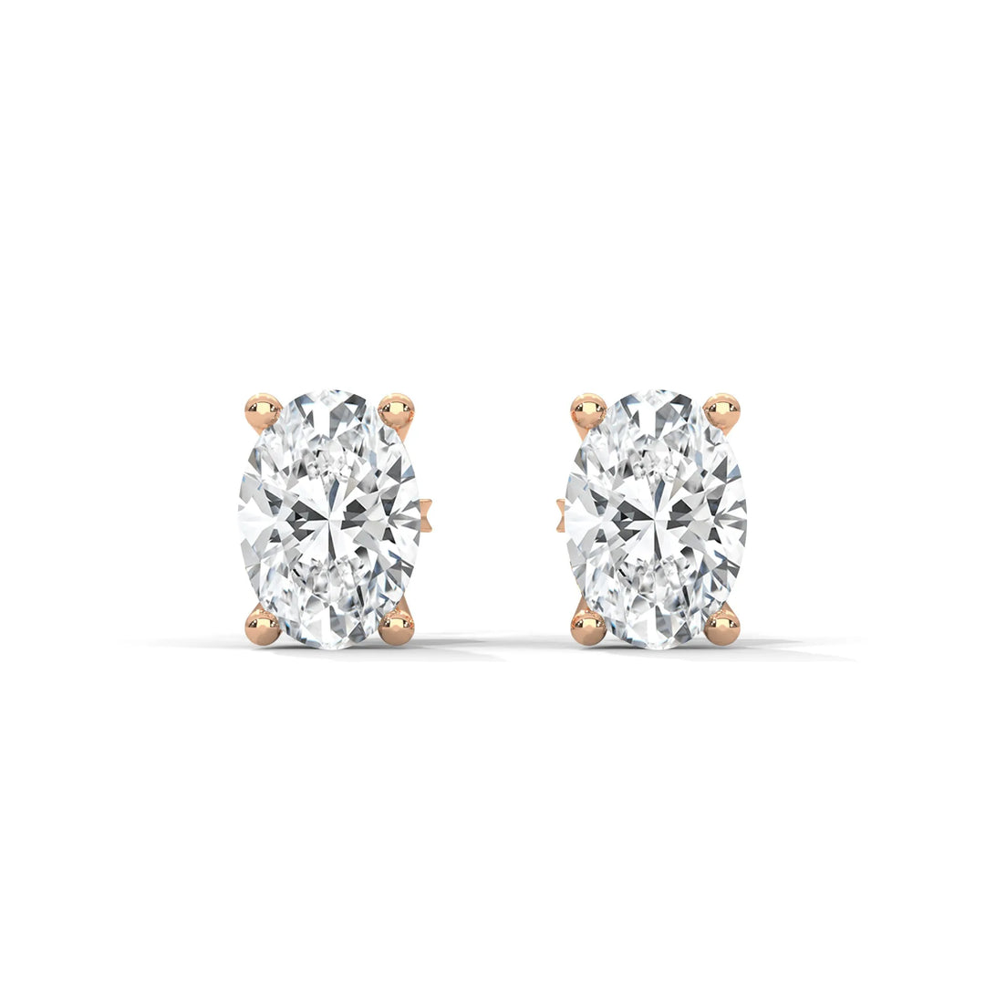 A pair of oval cut diamond stud earrings with rose gold settings on a white background.