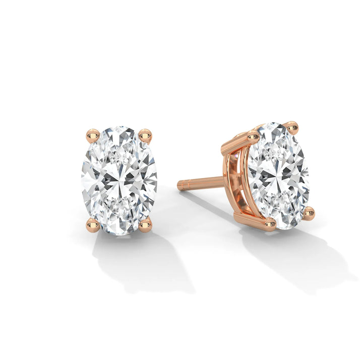 A pair of oval cut diamond stud earrings with rose gold settings.