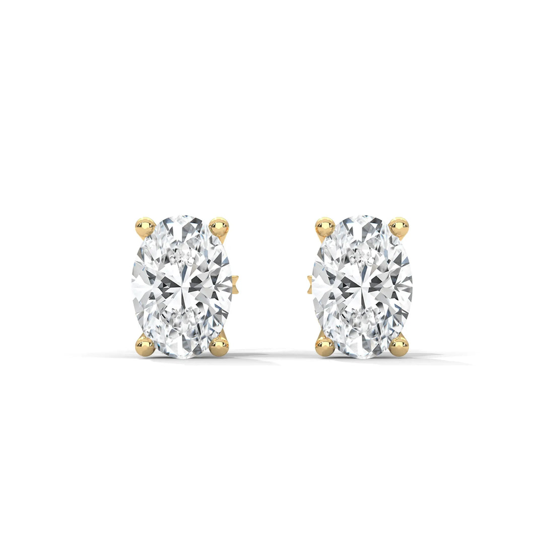 A pair of oval cut diamond stud earrings set in gold on a white background.