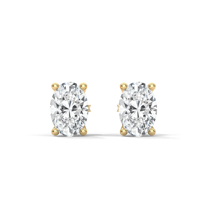 A pair of oval cut diamond stud earrings set in gold on a white background.