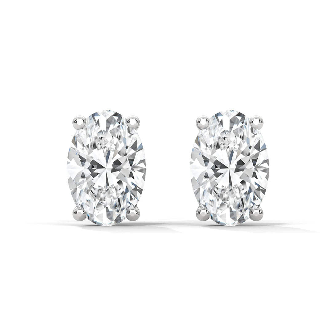 A pair of oval cut diamond stud earrings set in silver on a white background.