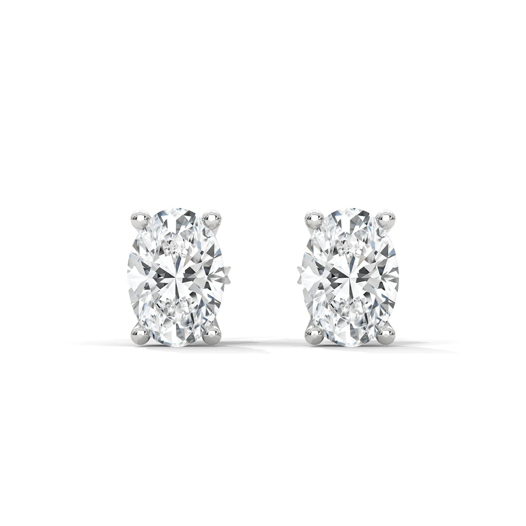 A pair of oval cut diamond stud earrings on a white background.