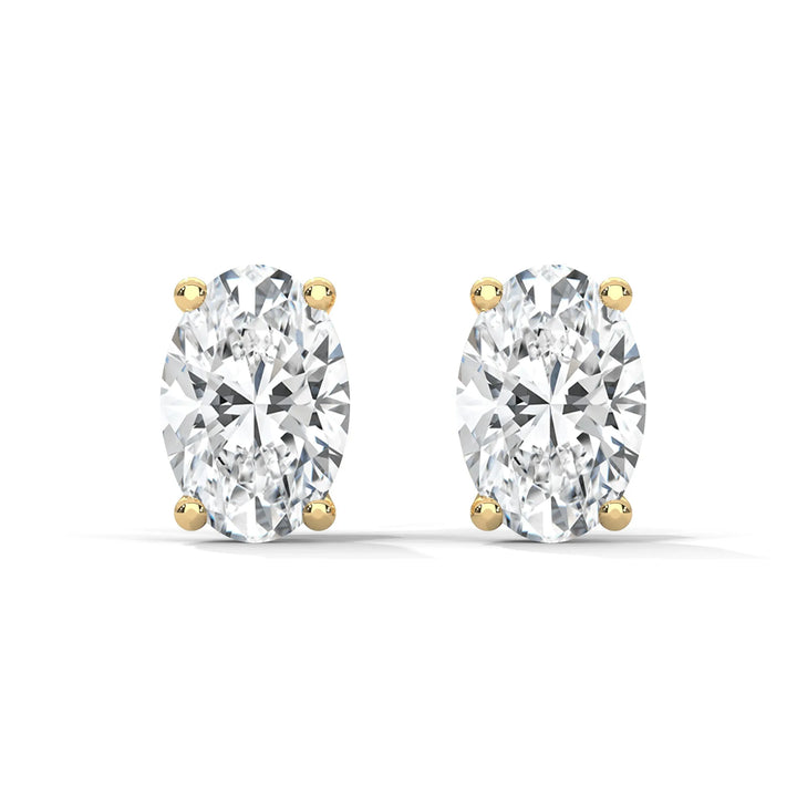 A pair of oval diamond stud earrings with gold settings on a white background.