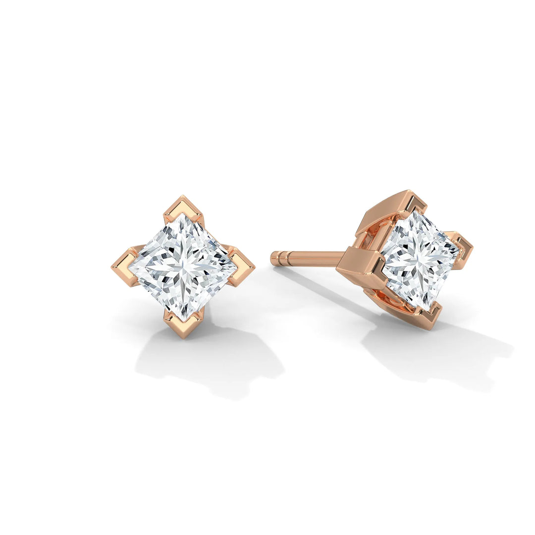 A pair of princess cut diamond earrings in a rose gold setting.