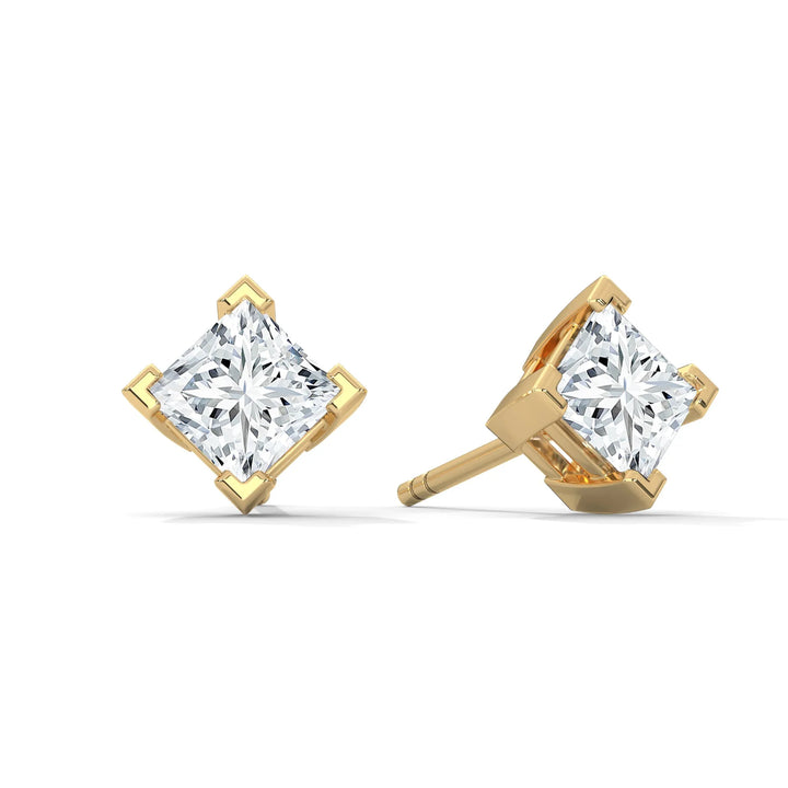 Pair of princess cut diamond earrings set in gold isolated on a white background.