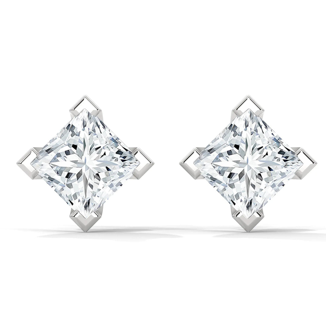 Pair of princess cut diamond earrings with silver settings on a white background.