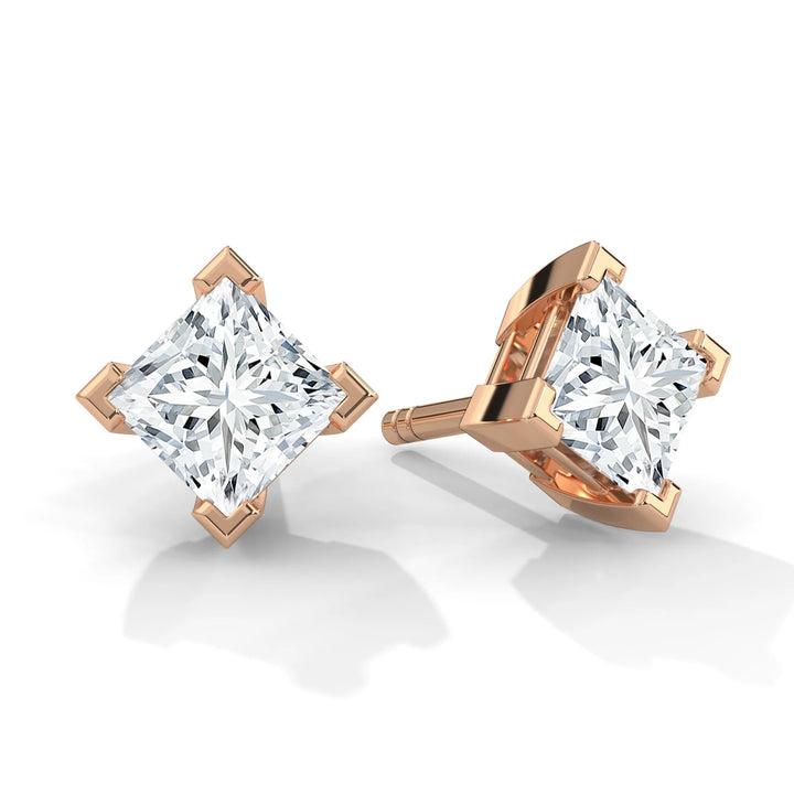 A pair of princess cut diamond stud earrings in a rose gold setting.