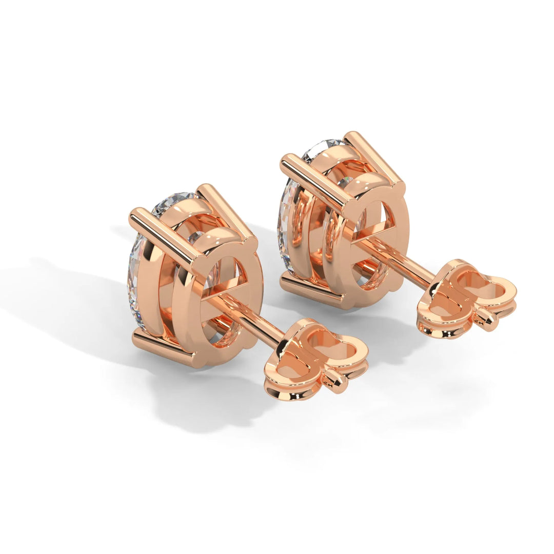 Pair of rose gold solitaire diamond earrings against a white background.