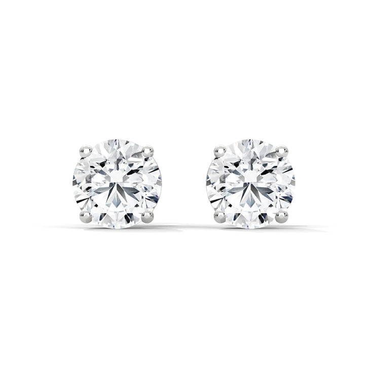 A pair of round cut diamond stud earrings in a four prong setting on a white background.