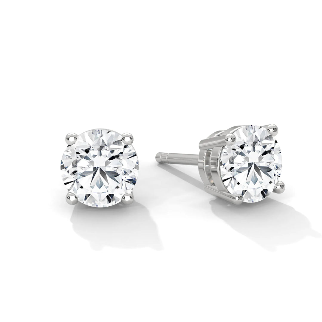 A pair of round cut diamond stud earrings in a four prong setting.