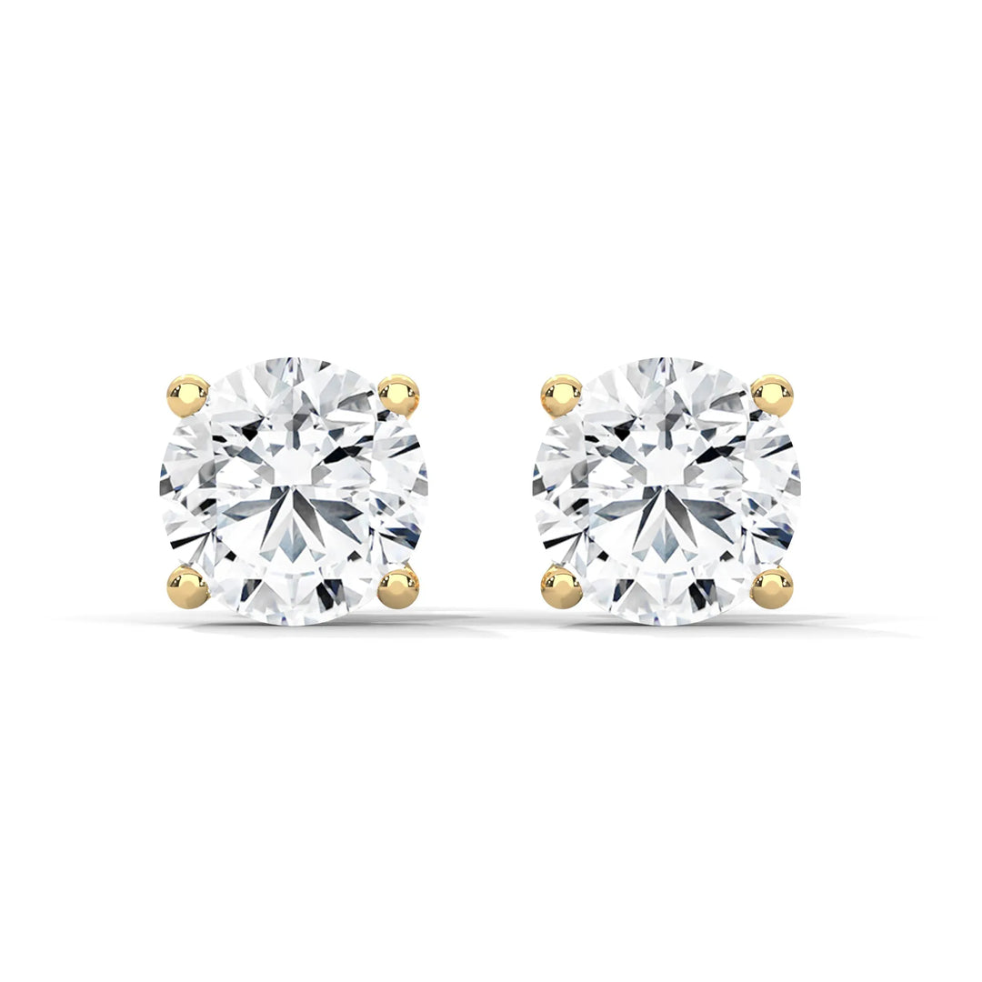 Pair of round cut diamond stud earrings with gold settings on a white background.