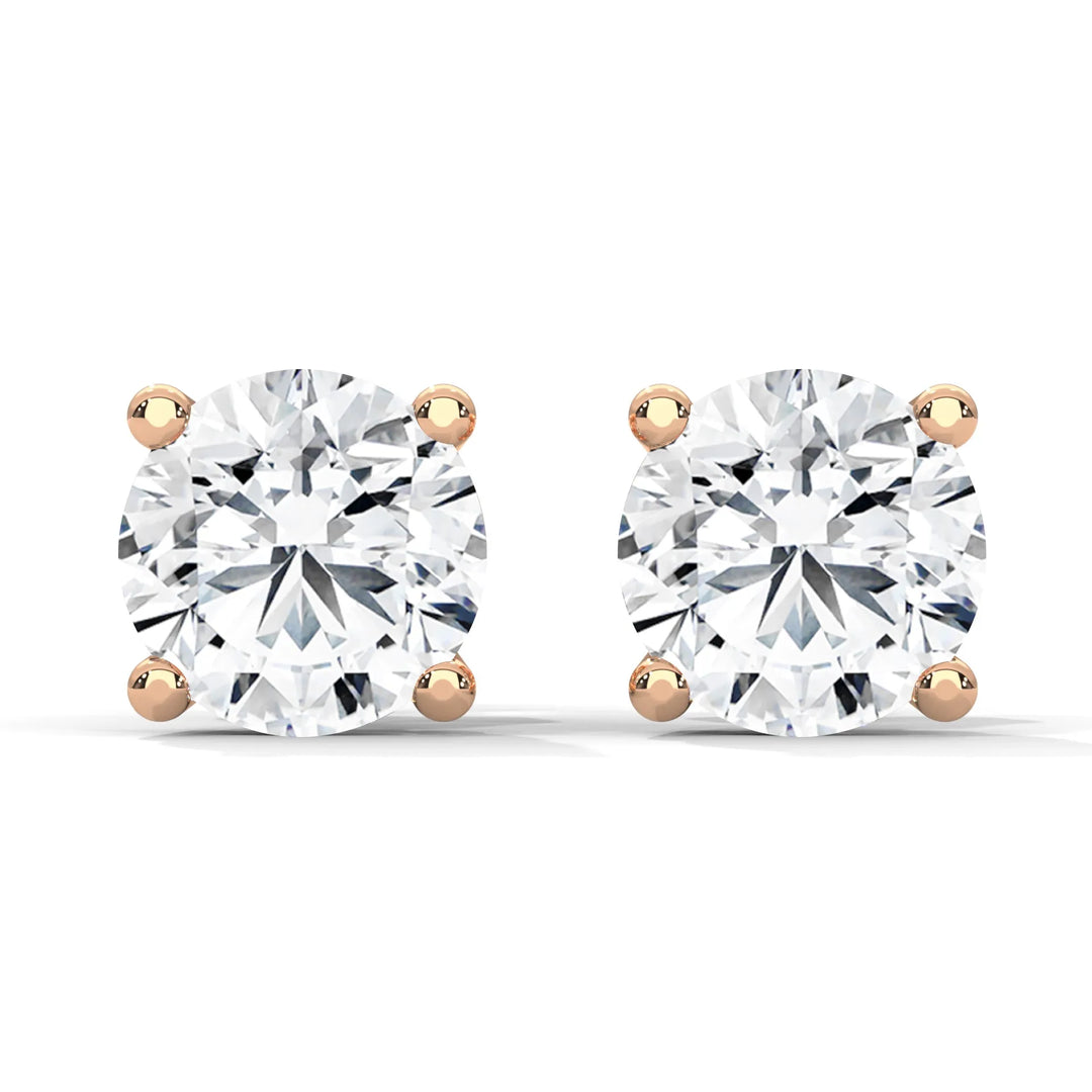 Pair of round cut diamond stud earrings with rose gold settings on a white background.