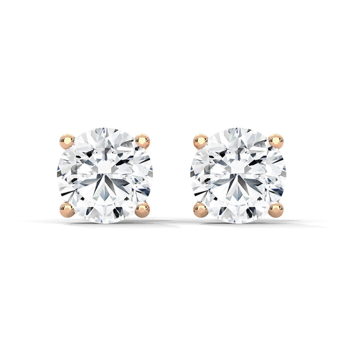 A pair of round cut diamond stud earrings with rose gold settings.