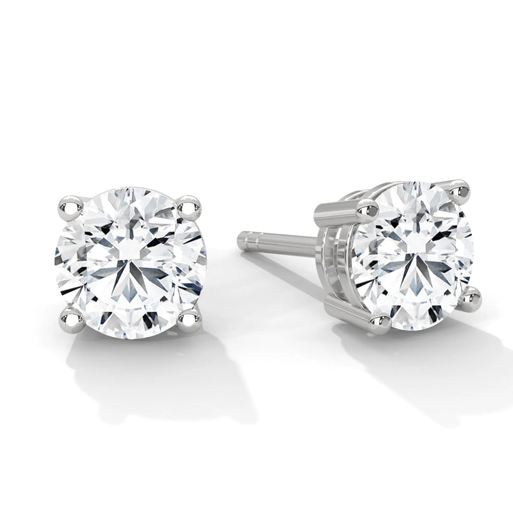 A pair of round cut diamond stud earrings set in a silver four prong setting.