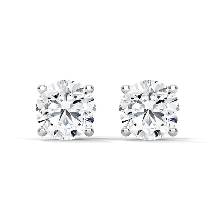 Pair of round cut diamond stud earrings with silver settings on a white background.