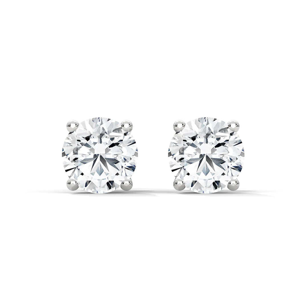 A pair of round cut diamond stud earrings on a white background.