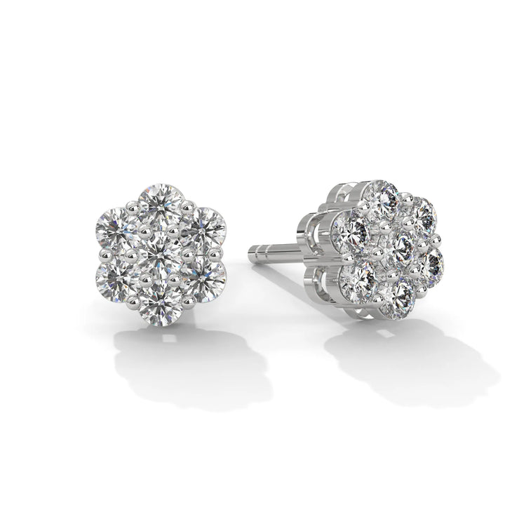 A pair of silver flower shaped diamond earrings on a white background.