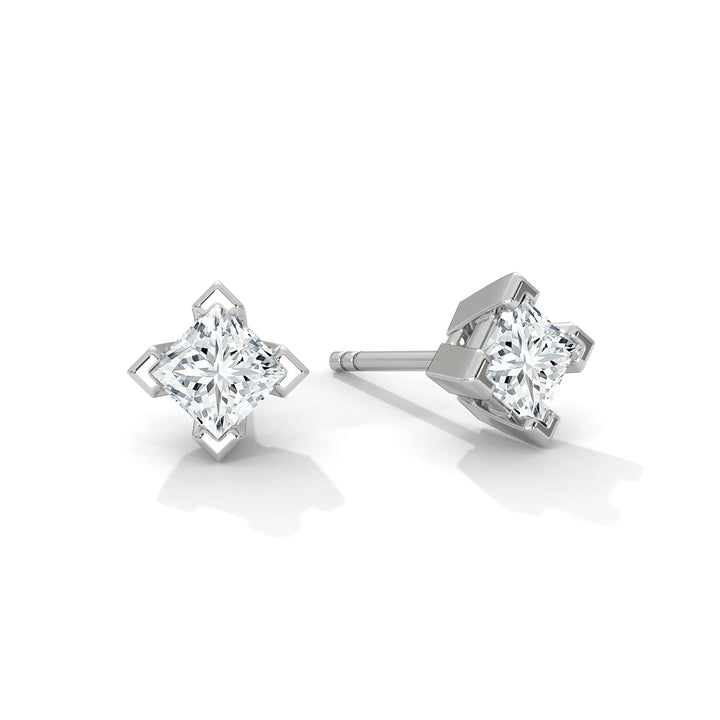 A pair of star shaped diamond stud earrings on a white background.