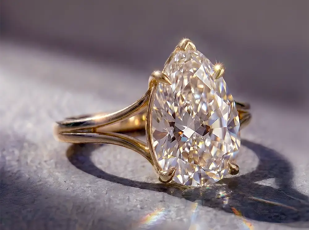 Close-up of a gold solitaire engagement ring featuring a sparkling pear-cut diamond in natural light
