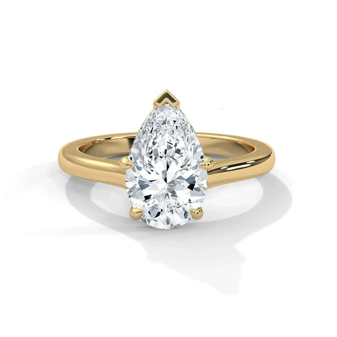 A pear-shaped diamond ring set in a gold band is displayed against a white background. The diamond sparkles, conveying elegance and luxury.