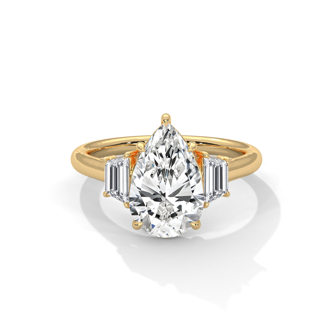 A pear-shaped diamond ring set in gold, flanked by two baguette-cut diamonds on each side, reflecting elegance and luxury against a white background.