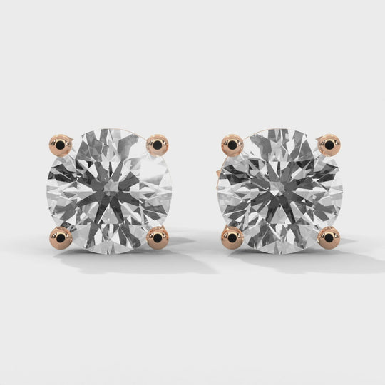 A pair of round cut diamond stud earrings with rose gold settings.