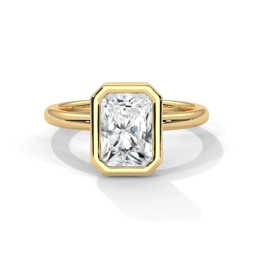 A radiant-cut diamond ring with a gold band sits centered against a white background, featuring a bezel setting that emphasizes elegance and luxury.