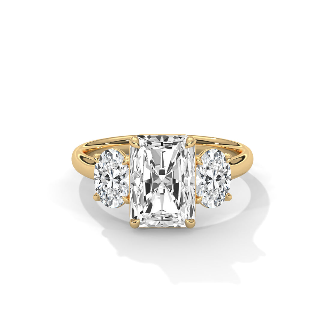 A radiant-cut diamond ring with two oval side diamonds, set on a gold band. The design is elegant and luxurious, showcasing brilliance and clarity.