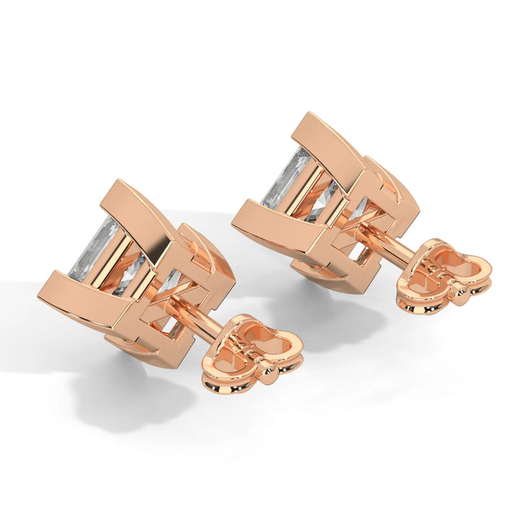 Rose gold cufflinks with a rectangular, clear gemstone on a white background.