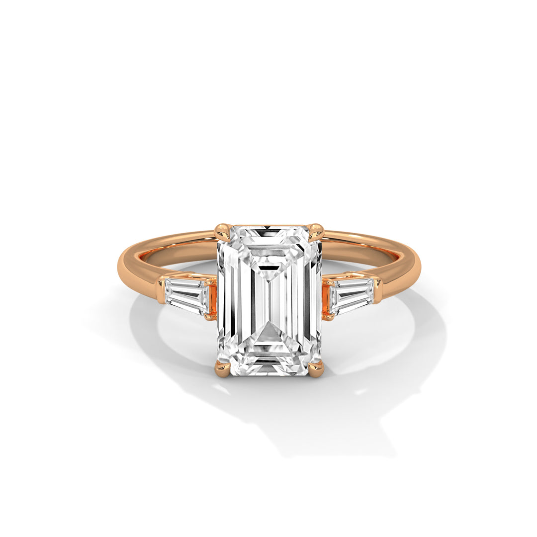 Rose gold ring with a central emerald-cut diamond flanked by two baguette diamonds. The elegant design conveys luxury and sophistication.