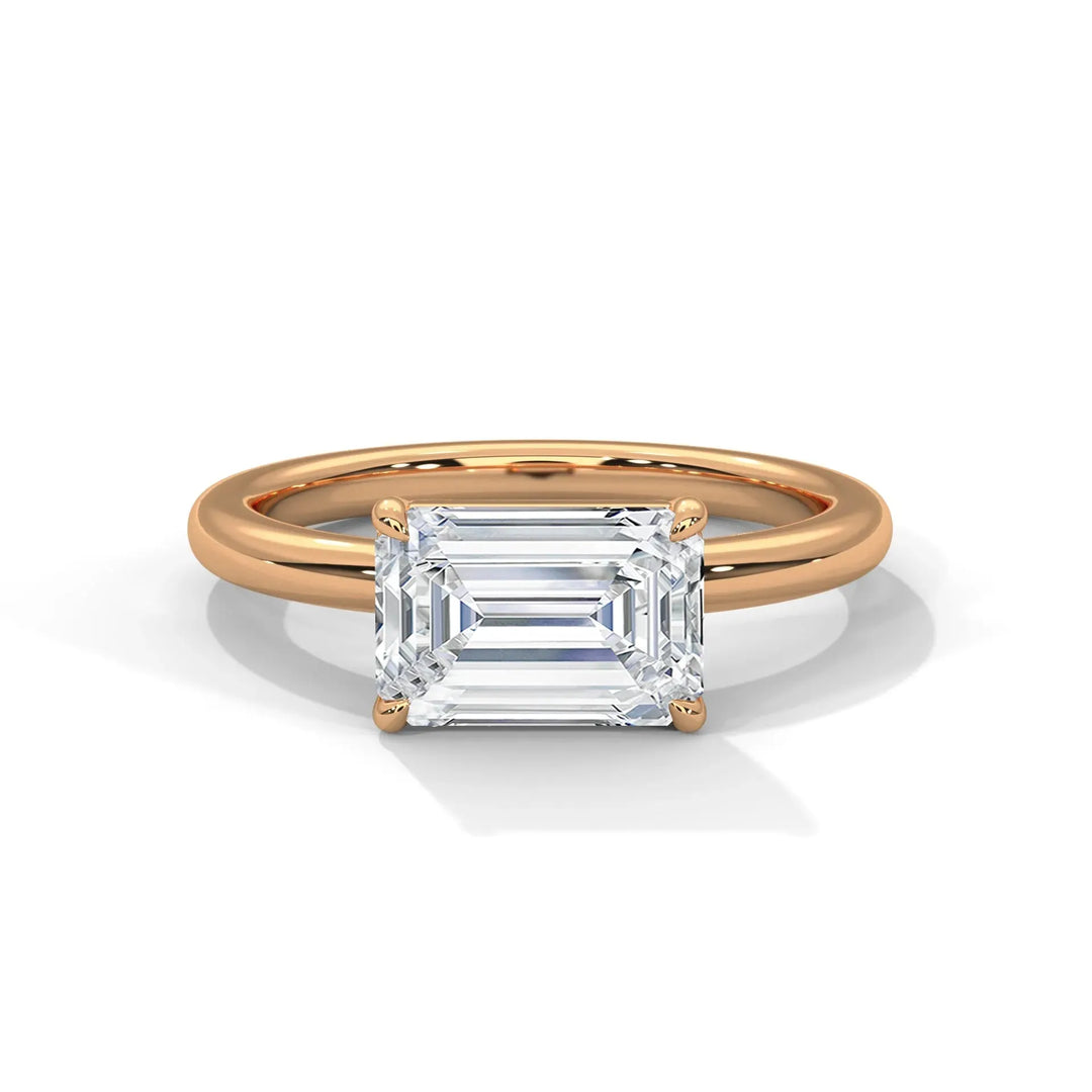 A rose gold ring with a large, rectangular emerald-cut diamond set in four prongs is displayed against a white background, exuding elegance and luxury.