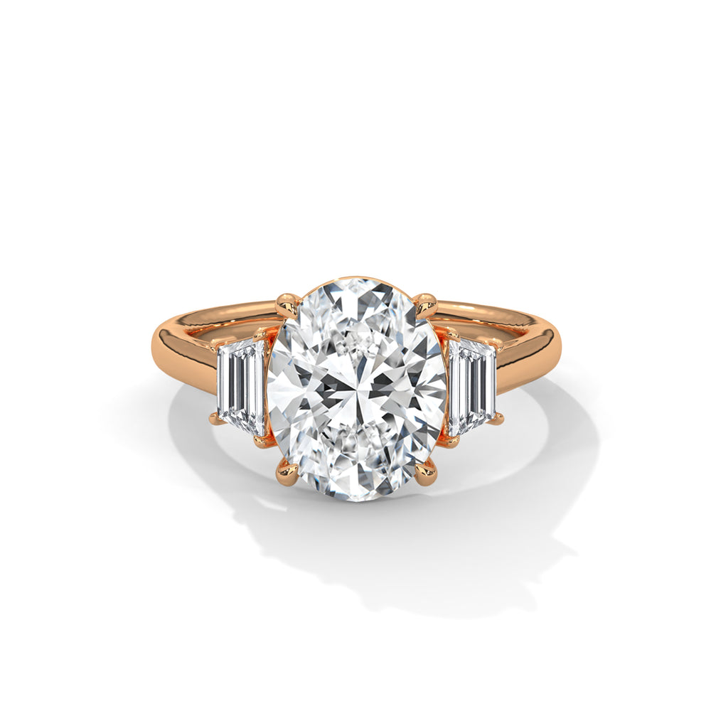 A rose gold ring with an oval diamond centerpiece, flanked by two baguette diamonds, exudes elegance and sophistication against a white background.