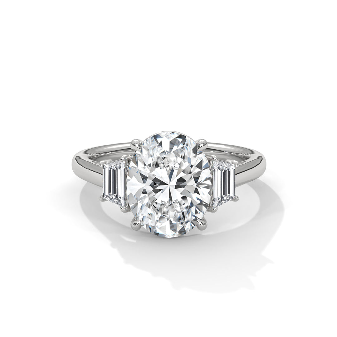 Silver engagement ring with a large oval diamond centerpiece, flanked by two rectangular baguette diamonds. Elegant, luxurious, and sparkling.