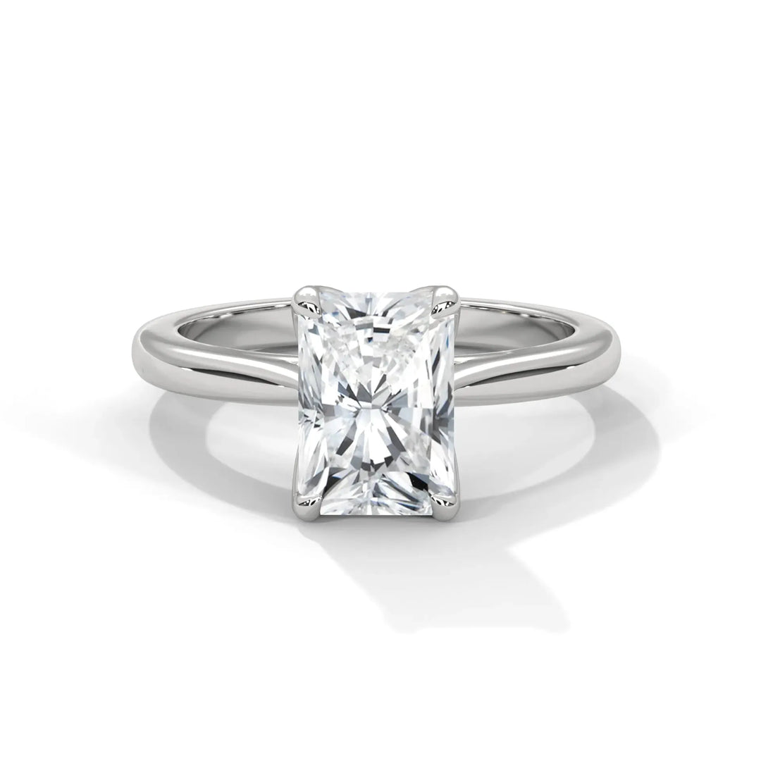 A silver engagement ring with a radiant-cut diamond center stone, set on a simple band, reflecting light beautifully, conveys elegance and sophistication.