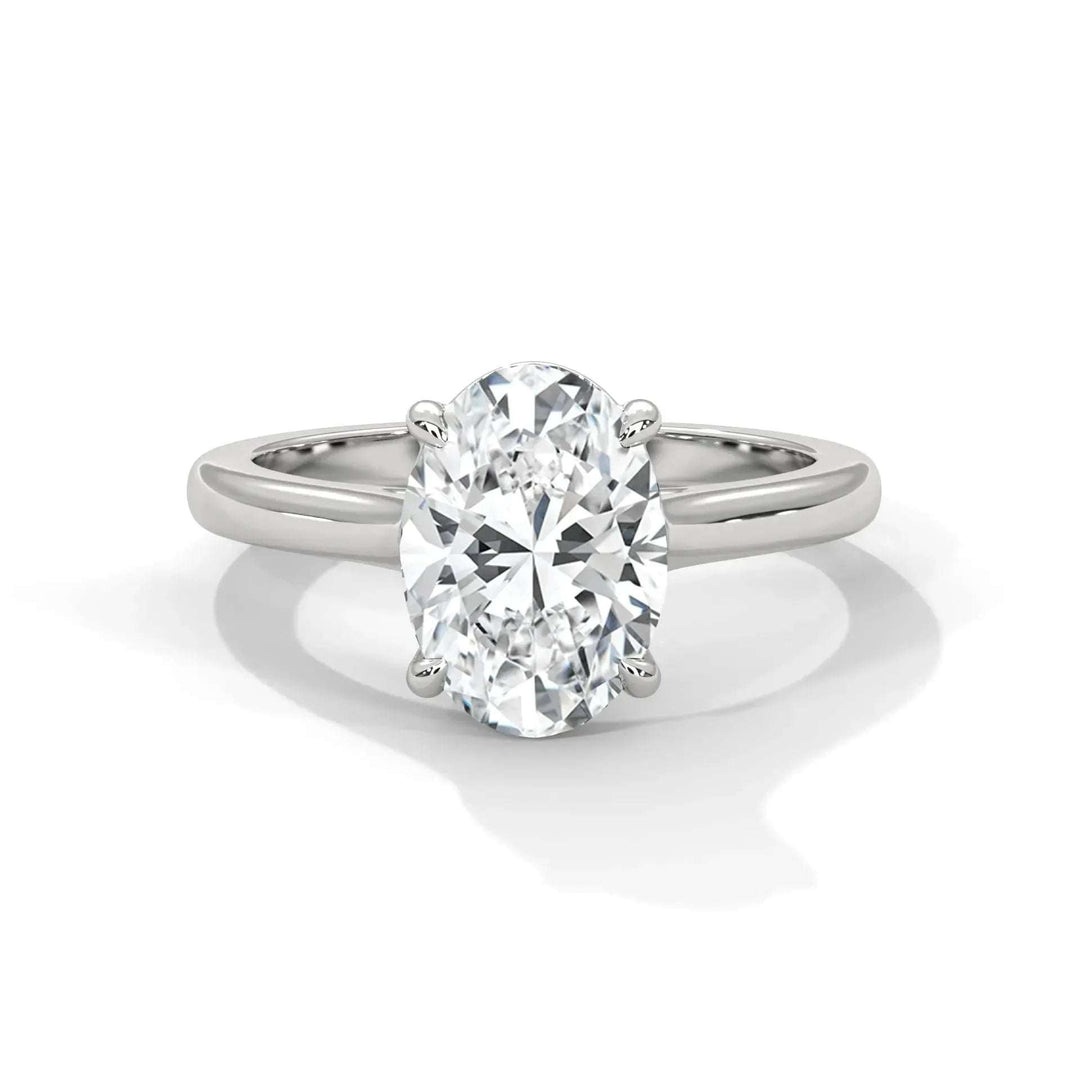 A sleek silver band ring featuring a sparkling oval diamond solitaire in a four-prong setting. The ring conveys elegance and timeless sophistication.