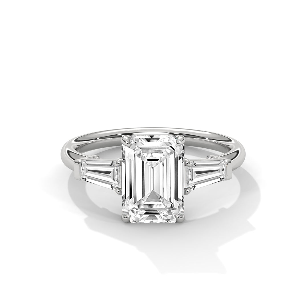 A sleek silver ring with a large emerald-cut diamond at the center, flanked by two tapered baguette side stones, exuding elegance and sophistication.