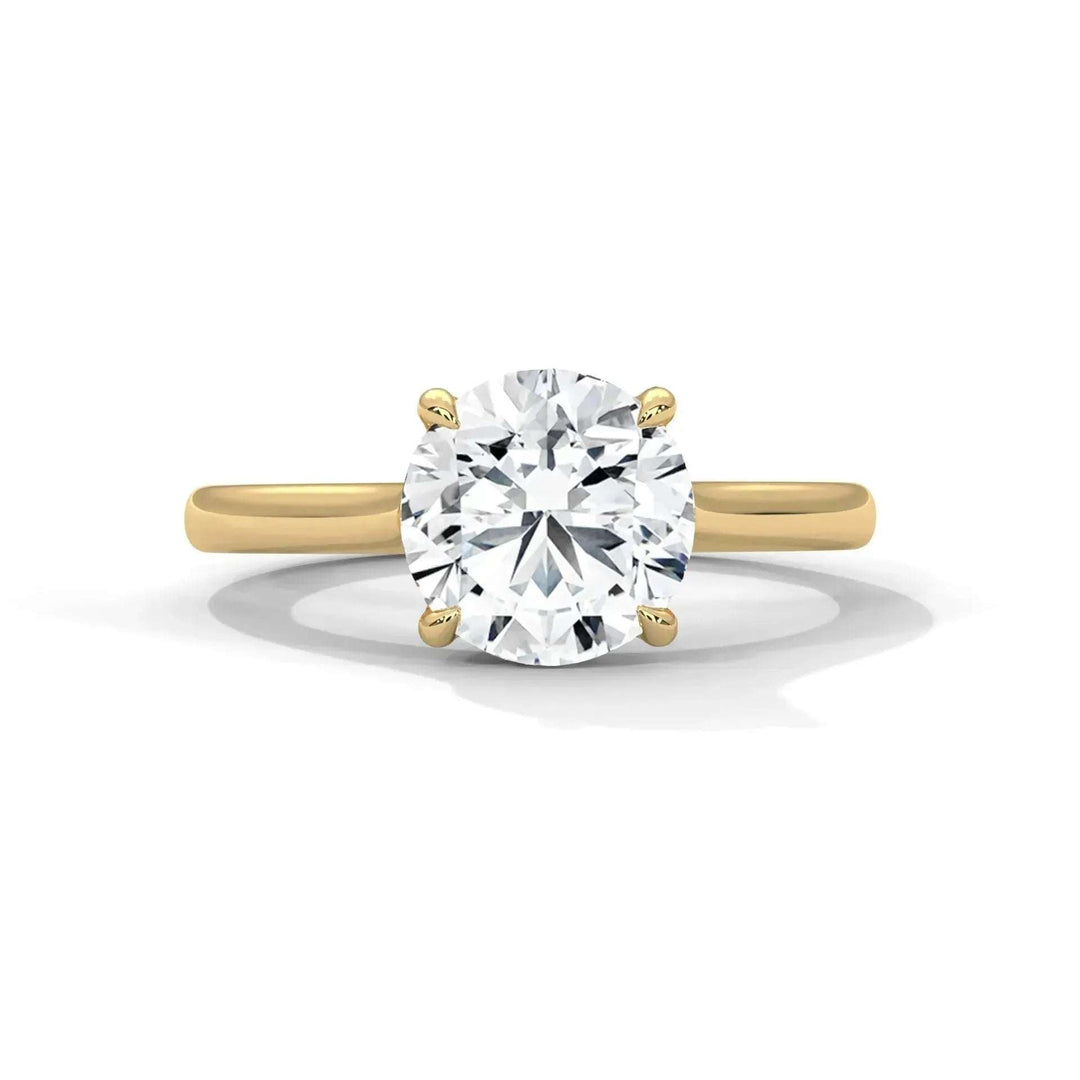 A solitaire diamond engagement ring featuring a large, round-cut diamond set in four prongs on a simple gold band, conveying elegance and sophistication.