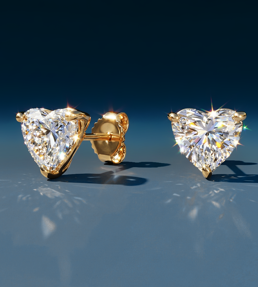 Heart-shaped diamond earrings set in gold, sparkling against a gradient blue background, conveying elegance and luxury.