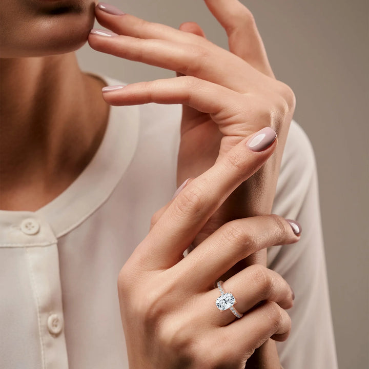 A close-up of a woman's hand featuring a stunning long cushion 14k rose gold diamond ring set in a Sun Belt design, emphasizing its luxurious appeal.