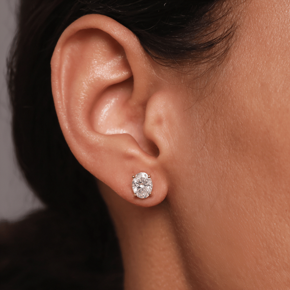 Close-up of ear wearing oval lab grown diamond earring in 14k gold four-prong setting