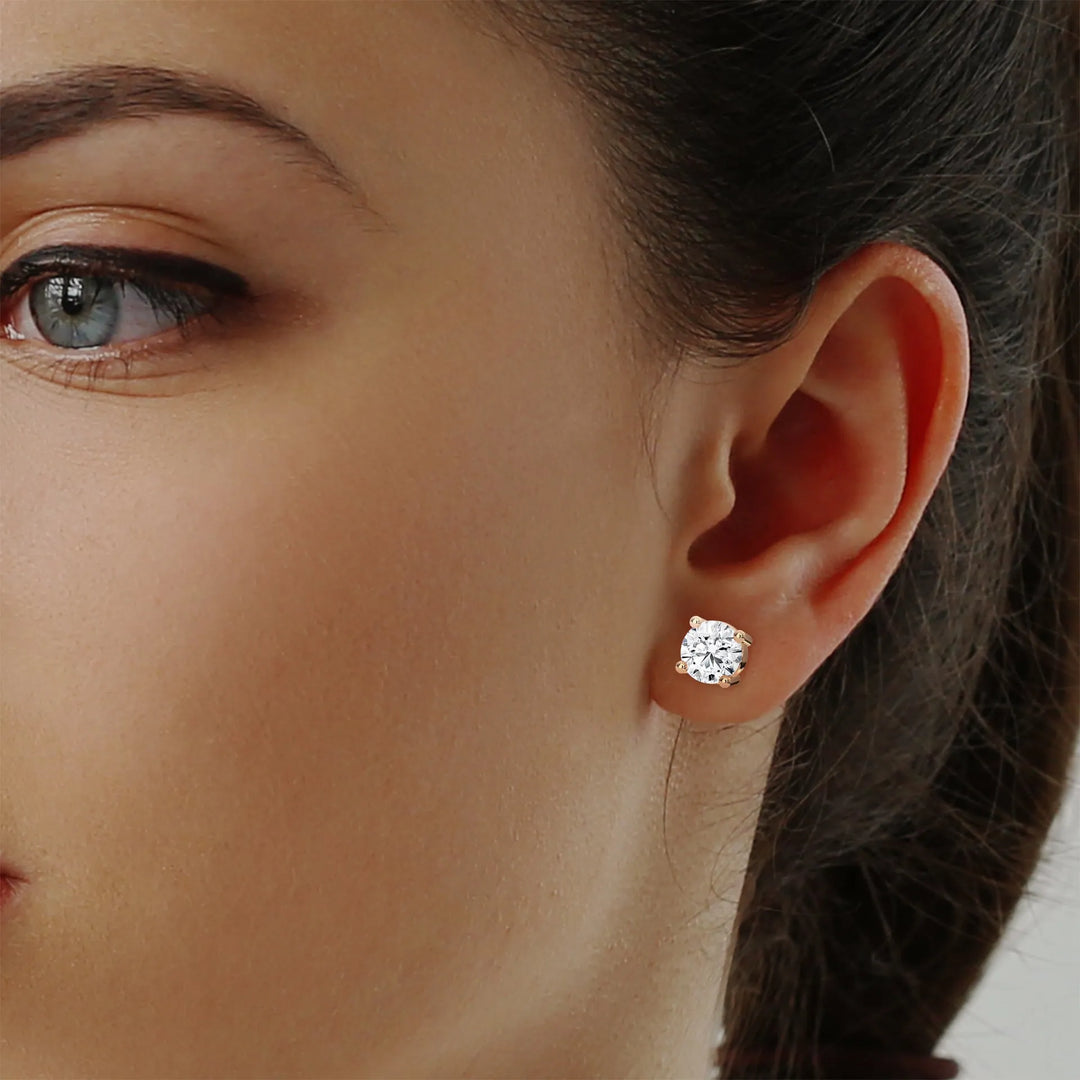 A woman elegantly showcases a pair of sparkling diamond stud earrings enhancing her sophisticated appearance.